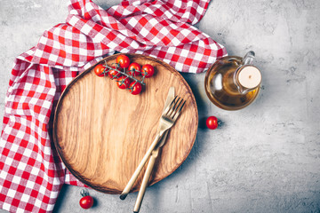 Empty wooden plate, cutlery and red checkered napkin on concrete background, Top view, flat lay. Toned image