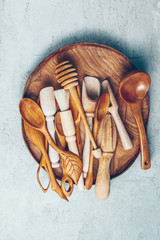 Set of wooden kitchen utensils in wooden plate on gray concrete background. Top view. Flat lay. Copy space.