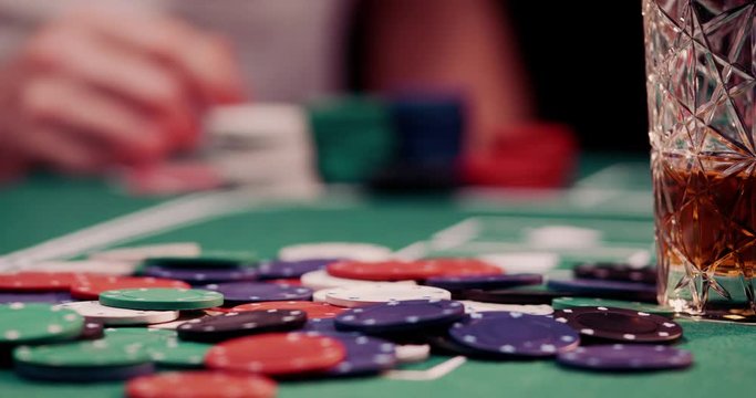 Close up of poker chips got thrown by a gambler on a heap of chips in the middle of the poker table shot in 4k super slow motion