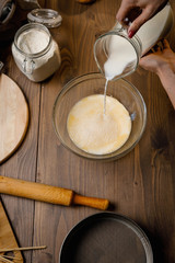 The confectioner prepares the dough, bread, cakes. Preparation and work with flour, eggs, milk and ingredients. Delicious food, recipes, cooking, gastronomy, on a dark background and wooden table.