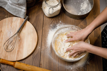 The confectioner prepares the dough, bread, cakes. Preparation and work with flour, eggs, milk and ingredients. Delicious food, recipes, cooking, gastronomy, on a dark background and wooden table.