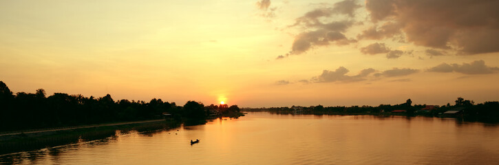 Fototapeta na wymiar Beautiful sunset above rural river view with fisherman riding boat