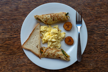 Tropical breakfast of scrambled eggs and banana pancakes in hotel restaurant
