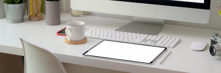 Cropped shot of comfortable office desk with blank screen tablet and office supplies