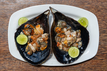 Raw clam meat in a large seashell served for food at a local restaurant on the island of Zanzibar, Tanzania, East Africa