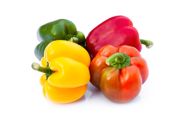 Pile of fresh whole green, red, yellow bell peppers or capsicum isolated on white background.