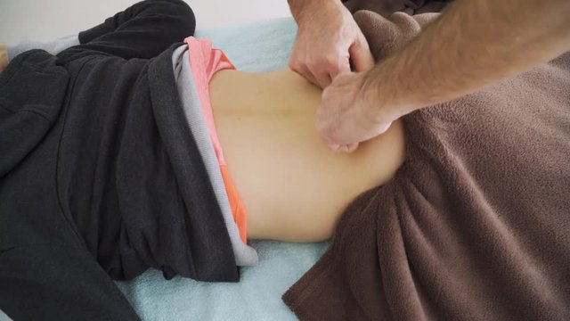 The masseuse hands massage back and spine to caucasian woman in a medical salon. Concept of therapeutic massage and relaxation.