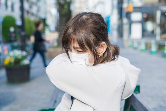 口をひじに当ててせきをする女性