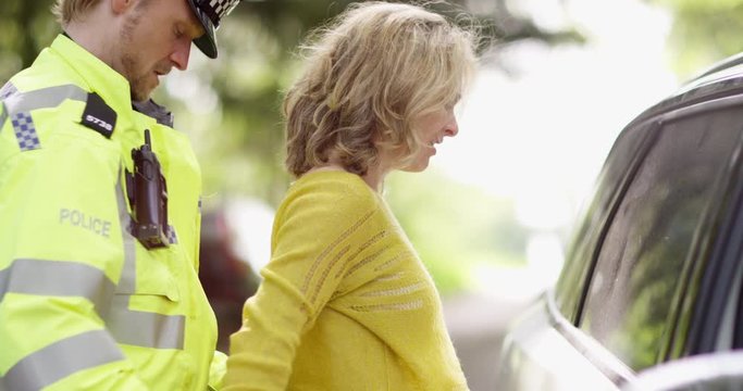 4K Policeman arresting a female driver & putting on the handcuffs. Slow motion.