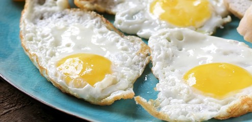 sunny breakfast life style, fried eggs and yellow cherry tomatoes. on a blue plate. yellow and blue