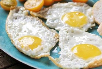 sunny breakfast life style, fried eggs and yellow cherry tomatoes. on a blue plate. yellow and blue