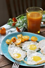sunny breakfast life style, fried eggs and yellow cherry tomatoes. on a blue plate. yellow and blue