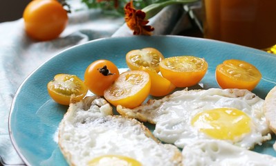 sunny breakfast life style, fried eggs and yellow cherry tomatoes. on a blue plate. yellow and blue