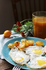 sunny breakfast life style, fried eggs and yellow cherry tomatoes. on a blue plate. yellow and blue