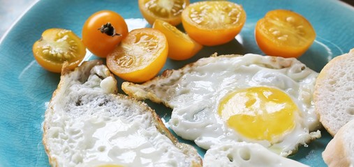 sunny breakfast life style, fried eggs and yellow cherry tomatoes. on a blue plate. yellow and blue