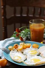 sunny breakfast life style, fried eggs and yellow cherry tomatoes. on a blue plate. yellow and blue