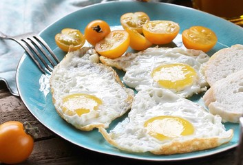 sunny breakfast life style, fried eggs and yellow cherry tomatoes. on a blue plate. yellow and blue