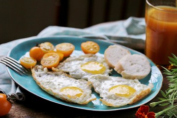sunny breakfast life style, fried eggs and yellow cherry tomatoes. on a blue plate. yellow and blue