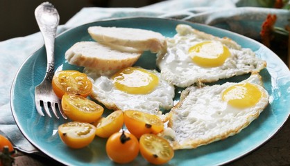 sunny breakfast life style, fried eggs and yellow cherry tomatoes. on a blue plate. yellow and blue
