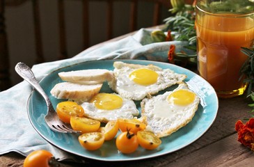 sunny breakfast life style, fried eggs and yellow cherry tomatoes. on a blue plate. yellow and blue