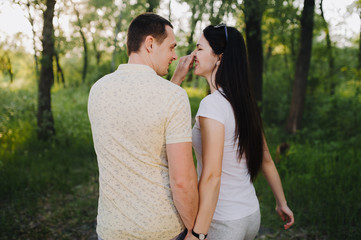 Lovers guy jokes and pinches the girl by the nose, walking through the woods, in nature, in tracksuits for a walk, holding hands. Love story newlyweds. Photography, concept.