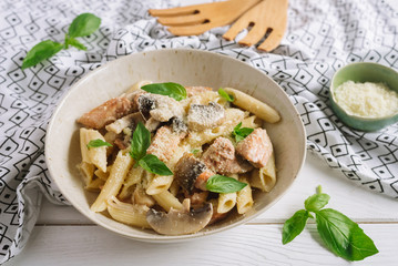 Penne with slices of chicken meat and turkey chunks and mushrooms in a creamy sauce, grated cheese...