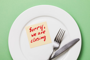 Note with text in a white plate and cutlery on a green background. Concept on the theme of the...