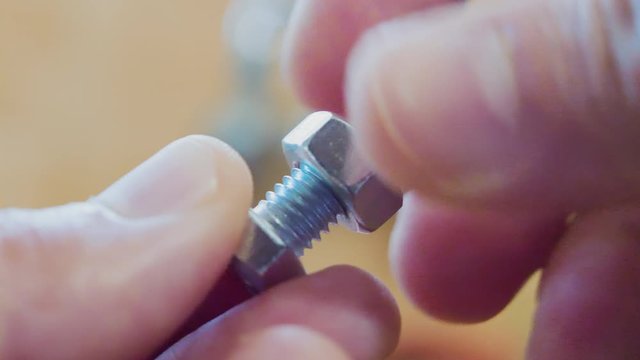 Adult Caucasian male fingers fastens bolt clockwise on hexagonal screw to end