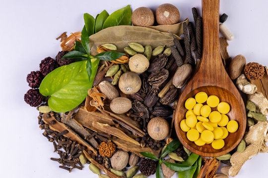 Herbal treatment concept. Ayurvedic medicines in wooden spoon and spices on white background