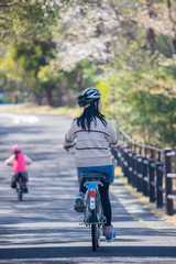 Fototapeta na wymiar 春の公園で自転車を乗っている子供姉妹二人