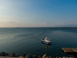 Naklejka premium Beautiful landscape view of a boat in calm waters of the ocean near to a pier