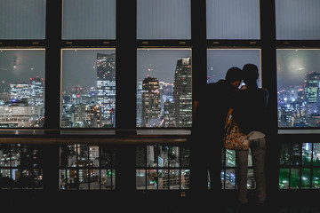 Fototapeta na wymiar Couple and panoramic view of Tokyo skyline by night from the Tokyo Tower Observation Deck, Japan