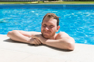  young man resting on edge of swimming pool