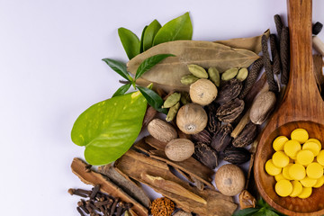 Traditional medicine concept. Top view closeup of  ayurvedic drugs in wooden spoon and spices on white background