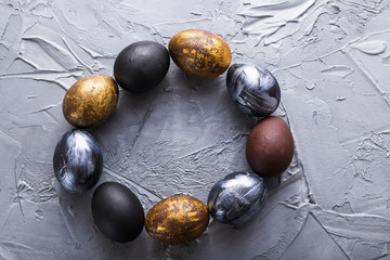 Holidays, traditions and Easter concept - Dark stylish easter eggs on grey background.