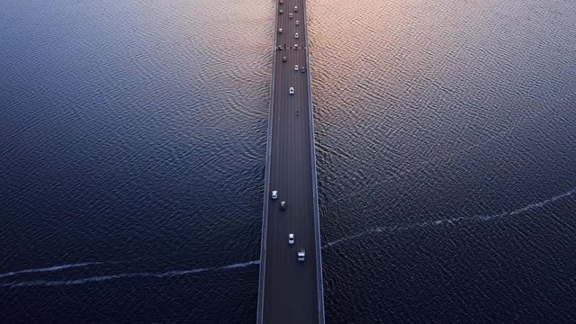 Aerial overhead of traffic over the Tasman bridge across the wide flowing Derwent river in Tasmania Australia, with bike, cars and trucks, crossing at sunset.