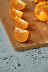 Pieces of mandarin on wooden board in morning sun rays, on white table