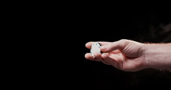 Close up of male gambling hand makes tricks with poker chips black background shot in 4k super slow motion