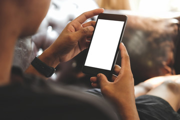 Cropped shot view of man hands holding smart phone with blank copy space screen for your text message or information content, female reading text message on cell telephone during in urban setting. 
