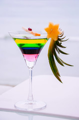 Fresh vibrant colours summer cocktail in a glass on white bar counter natural light