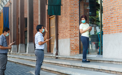 Asian middle aged people wearing mask and keep social distancing to avoid the spread of COVID-19