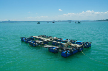 Fish cage floats and boats float in blue sea