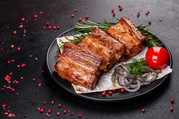 Fried ribs with rosemary, onion, sauce on a concrete background
