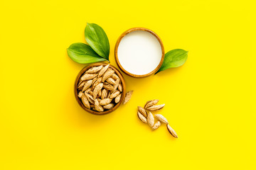 Alternative milk made from almond. Drink near unpeeled on yellow table top-down