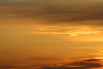 Sun below the horizon and clouds in the fiery dramatic orange sky at sunset or dawn backlit by the sun. Place for text and design.