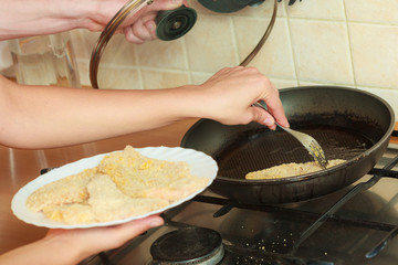Human frying breaded chicken cutlet.