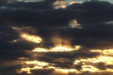 The suns rays pass through the dark clouds. Beautiful dramatic sky at sunset or sunrise.
