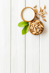 Alternative milk made from almond. Drink near unpeeled on white wooden table top-down copy space