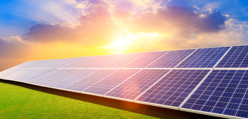Photovoltaic solar panels and green grass on sky background,green clean alternative energy concept.