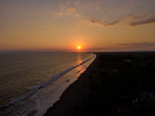 Beautiful sunset on the beach with the silhouette of the palm trees 